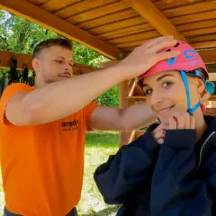 Przed przygodą w parku linowym Bielany, instruktor pomaga założyć kask.