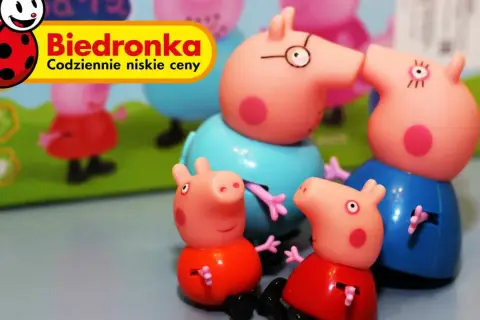 Urocza świnka Peppa zabawka z Biedronki. Rodzina świnek wesoło bawi się na tle zielonej trawy.