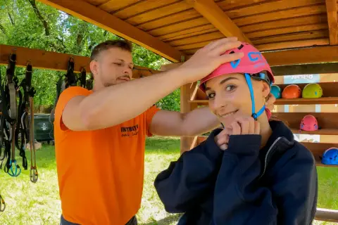 Przed przygodą w parku linowym Bielany, instruktor pomaga założyć kask.